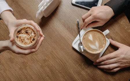 Two people having coffee; hands and cups only